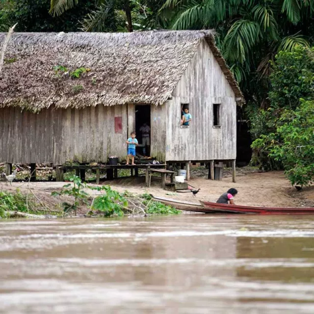 Kids next to hut and river in Amazon Rain Forest