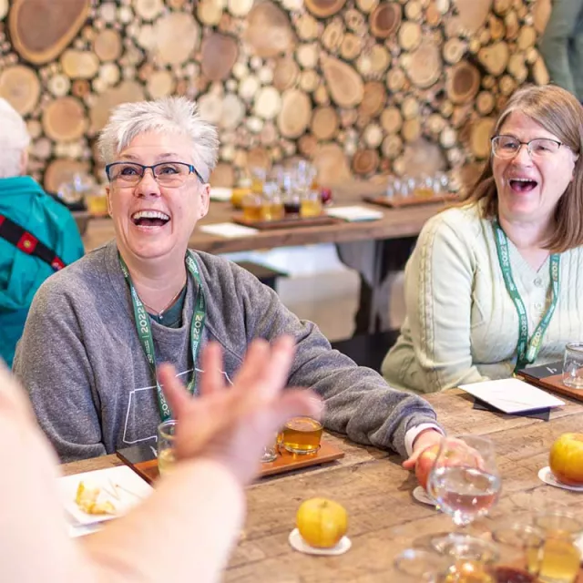 Woman laughing and chatting together over a wine tasting.