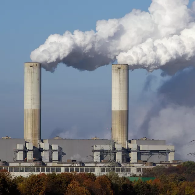 Industrial chimney stacks venting large clouds of smoke.