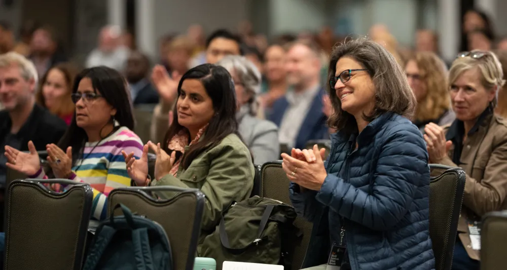 crowd of people at a conference clapping