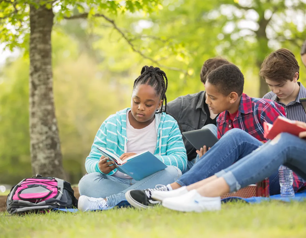 group of middle school students sitting under a tree and talking