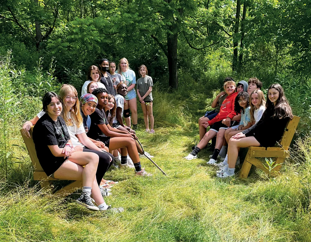 Group of students from Perkiomen Valley School District seating together in a wooded area known as Perkiomen Valley Woods.