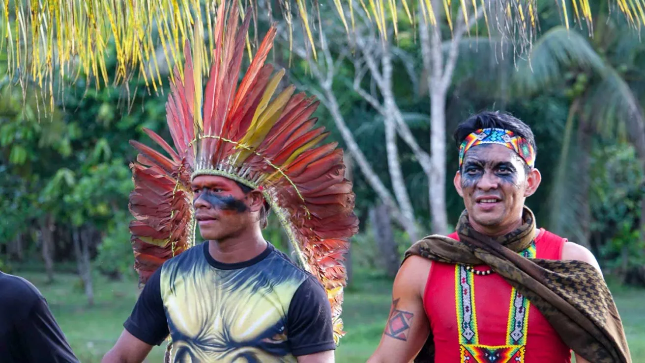 Two men in vibrant traditional costumes and elaborate headdresses pose together, showcasing their cultural heritage.