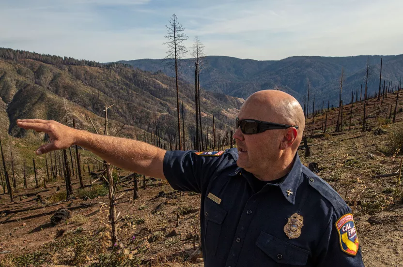 officer pointing out damage from fires in california