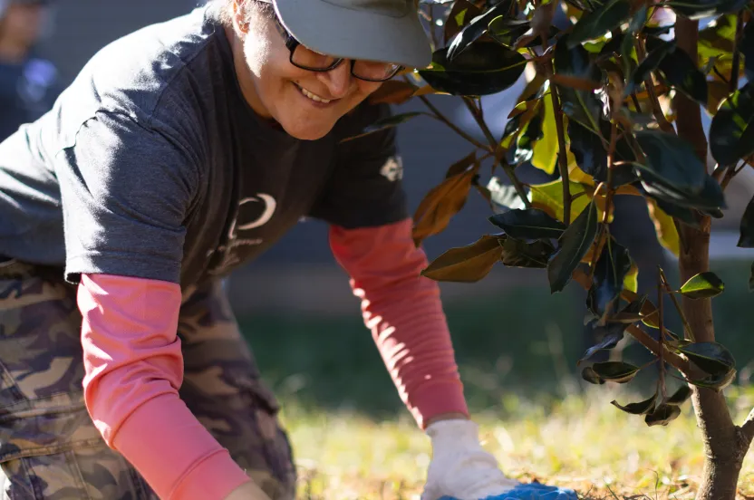 woman planting a tree in front of a new home.