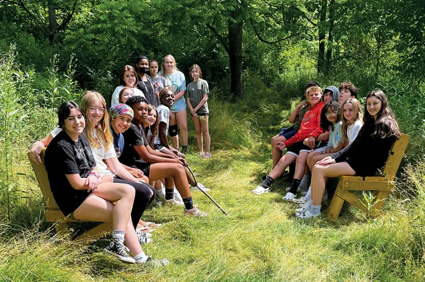 Group of students from Perkiomen Valley School District seating together in a wooded area known as Perkiomen Valley Woods.