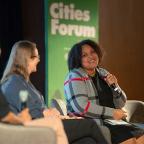 Woman holding microphone at a conference panel.